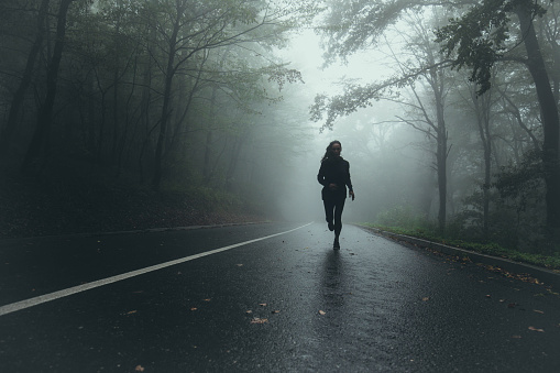 Determined athletic woman running through misty nature. Copy space.