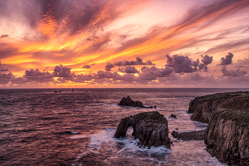 Sunset set at Lands End Cornwal with Enys Dodnan Arch, and longship lighthouse