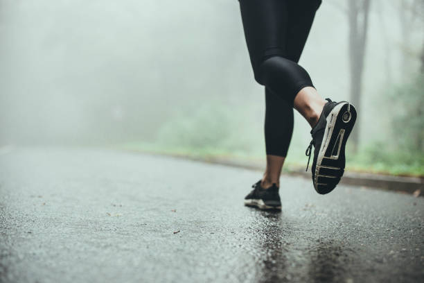 istock Unrecognizable athlete jogging on the road during rainy day. 1340654406