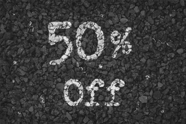 istock Black  and white coloured pebbles making a  rustic poster with text 50 % Off painted on gravel road with small swirls pattern, for SALE related vector backgrounds 1340656111