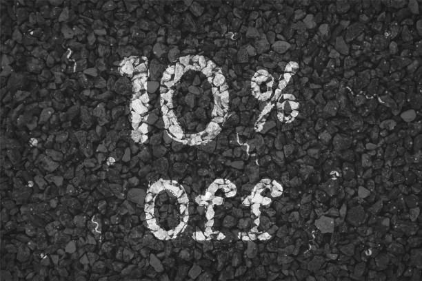 istock Black  and white coloured pebbles making a  rustic poster with text 10 % Off painted on gravel road with small swirls pattern, vector backgrounds 1340657404