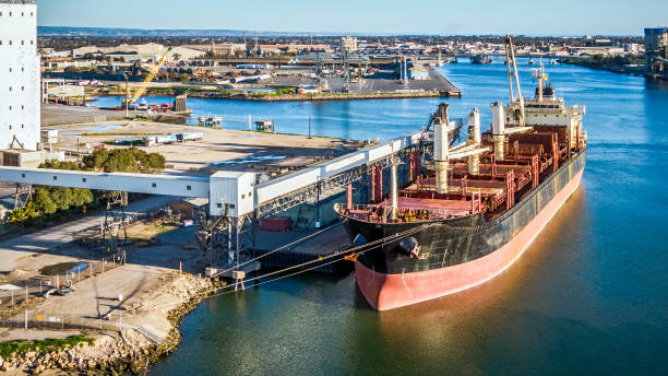 Panoramic aerial view of bulk carrier ship moored in river harbor, loading grain