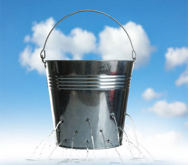 istock Leaky bucket with water against blue sky 1340657831