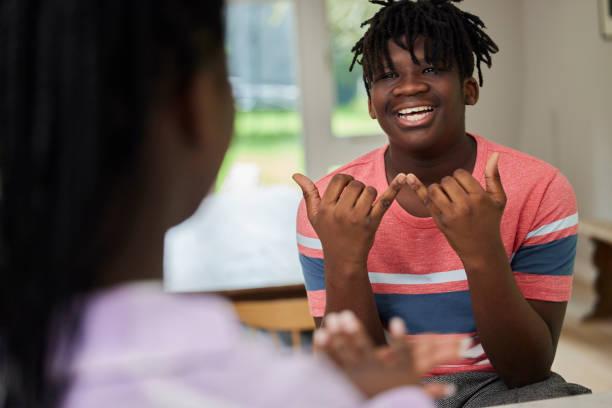 adolescent garçon et fille ayant une conversation en utilisant la langue des signes à la maison - deaf photos et images de collection