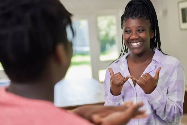 Photo of Teenage Girl And Boy Having Conversation Using Sign Language At Home