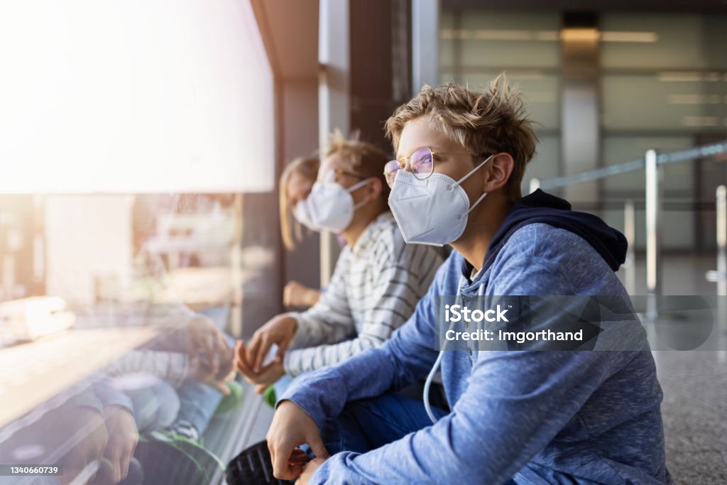Teenage boys and girl waiting at the airport and looking through the window Teenage boys and girl waiting at the airport. COVID-19 pandemic. Teenagers are wearing protective face masks.
Canon R5 N95 Face Mask Stock Photo