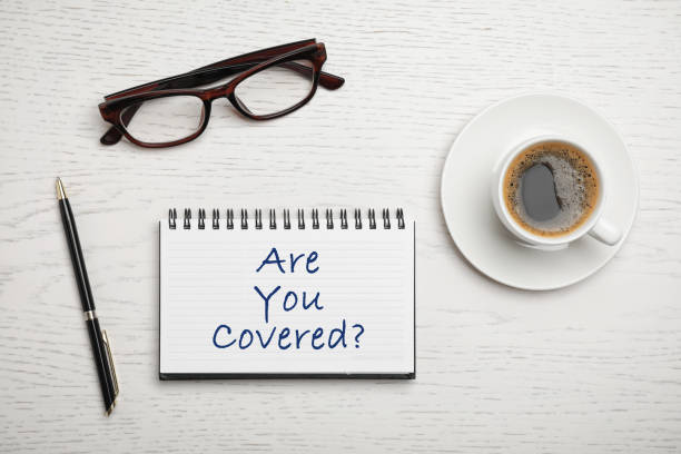 istock Flat lay composition with text ARE YOU COVERED? written in notebook on white wooden background. Insurance concept 1340660818