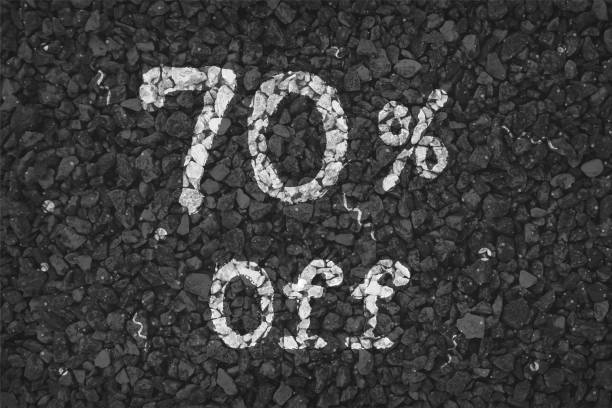 istock Black  and white coloured pebbles making a  rustic poster with text 70 % Off  painted on gravel road with small swirls pattern, vector backgrounds 1340661053