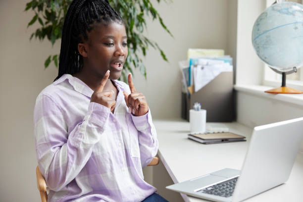 Teenage Girl Having Conversation Using Sign Language On Laptop At Home Teenage Girl Having Conversation Using Sign Language On Laptop At Home american sign language photos stock pictures, royalty-free photos & images