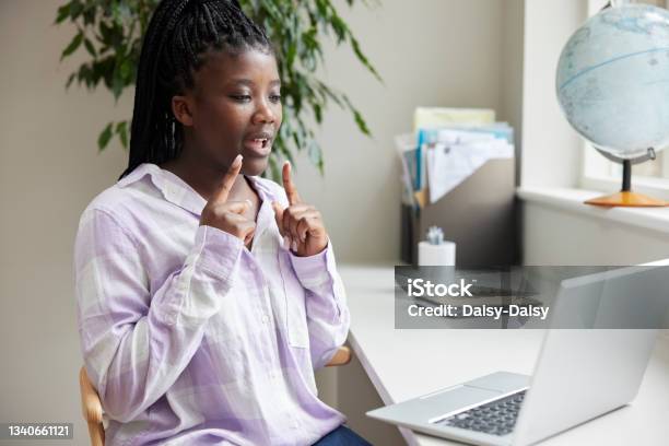 Teenage Girl Having Conversation Using Sign Language On Laptop At Home Stock Photo - Download Image Now