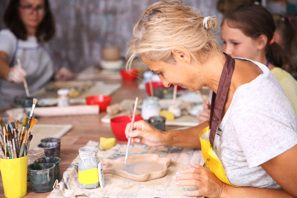 Mother and kid daughter molded from clay at pottery class
