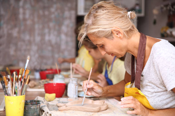 istock Mother and kid daughter molded from clay at pottery class 1340663780