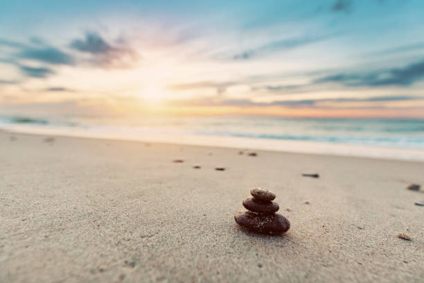 piedras zen en la playa tranquila al atardecer - conciencia plena fotografías e imágenes de stock