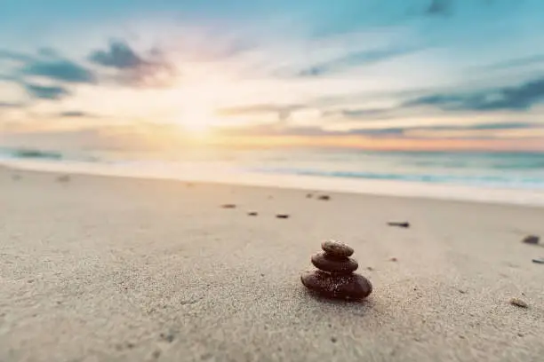 Zen stones on calm beach at sunset. Peaceful ocean, mindfulness