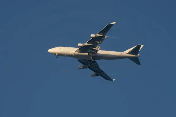 A commercial airliner at flight in a clear sky, in the sunlight, with its landing gear down.