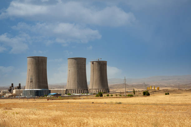 tours de refroidissement de centrales nucléaires, grandes cheminées à côté du champ de blé avec un ciel partiellement nuageux dans la province du kurdistan, iran - centrale nucléaire photos et images de collection