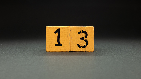 number thirteen in wooden cubes on black background