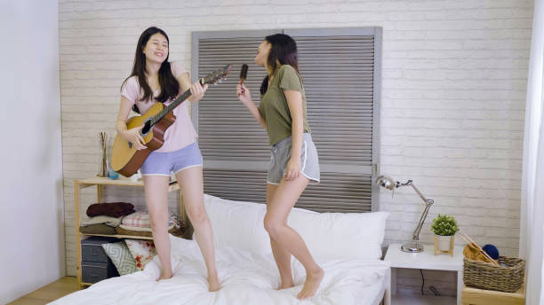 istock best friends dancing and playing guitar on bed 1340669778