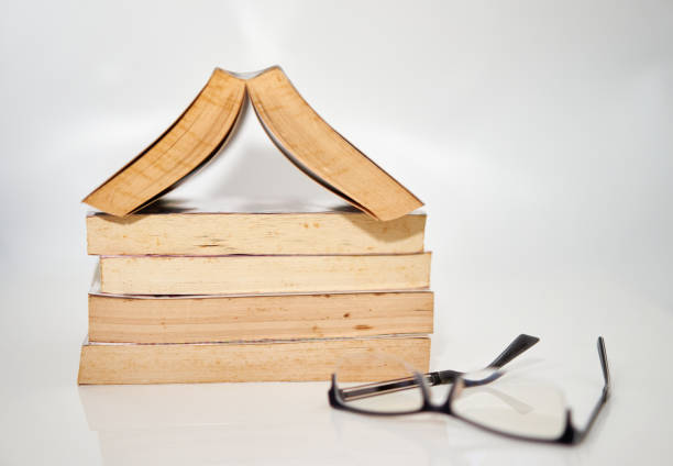 istock stack of books arranged pile on white background with glasses on top with open book 1340671571