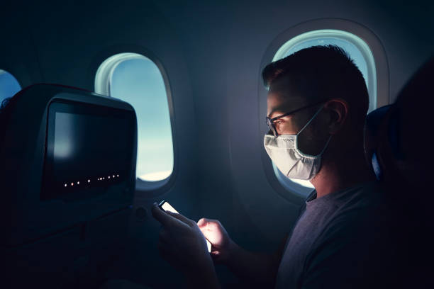 homme avec masque facial voyageant en avion - telephone cabin photos et images de collection