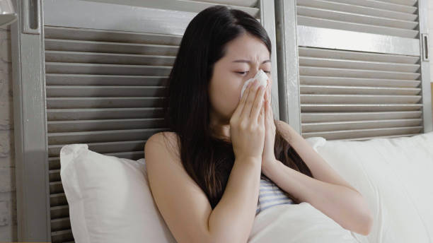 istock chinese female feeling unwell blowing her nose. 1340675237