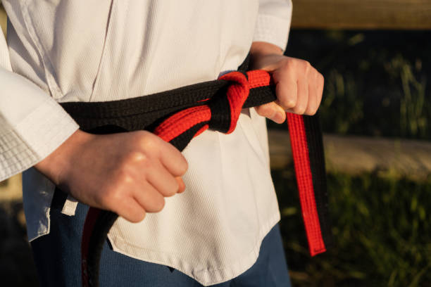 istock Karate boy attaching on a black belt on his taekwondo uniform before training outdoors. 1340675891