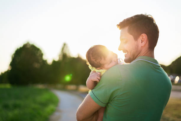 Family walk around the neighborhood. Single father is taking care of newborn baby while walking on sunset.