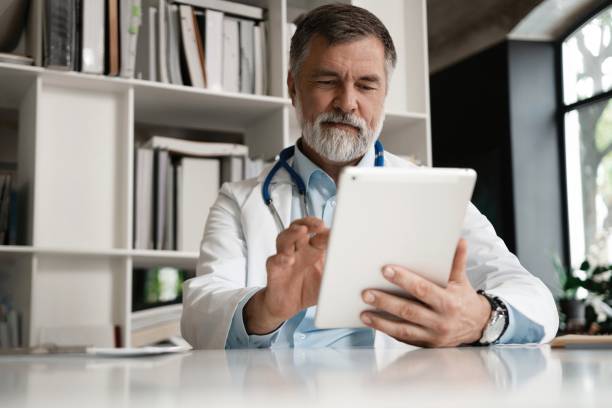 istock Cheerful mature doctor using digital tablet in clinic. 1340679293