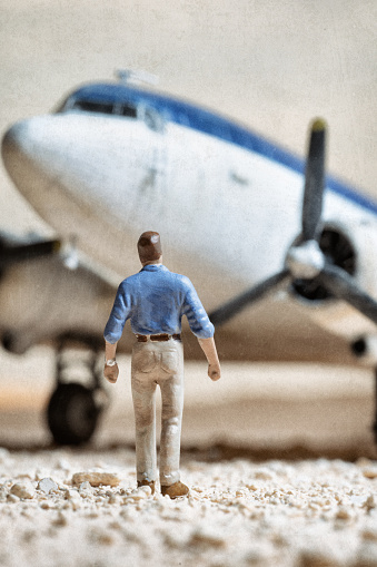 A miniature man in the desert eyes up a DC-3 Dakota aeroplane.