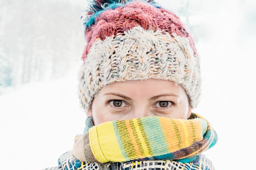 Portrait of happy young woman in winter. Snowing, tourism and travel concept. Smiling closeup female's face.