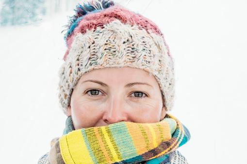 Portrait of happy young woman in winter. Snowing, tourism and travel concept. Smiling closeup female's face.