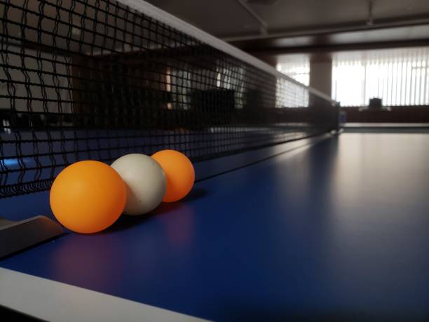 три желто-белых мяча для настольного тенниса на синем теннисном столе - table tennis table стоковые фото и изображения