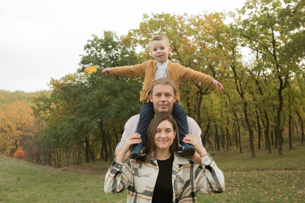 Fall. Close-up of happy family on the background of the autumn forest. Happy mom, dad and son are smiling. Fall. Close-up of happy family on the background of the autumn forest. Happy mom, dad and son are smiling. women lying down grass wood stock pictures, royalty-free photos & images