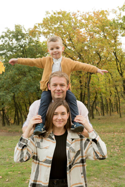 Fall. Close-up of happy family on the background of the autumn forest. Happy mom, dad and son are smiling. Fall. Close-up of happy family on the background of the autumn forest. Happy mom, dad and son are smiling. women lying down grass wood stock pictures, royalty-free photos & images