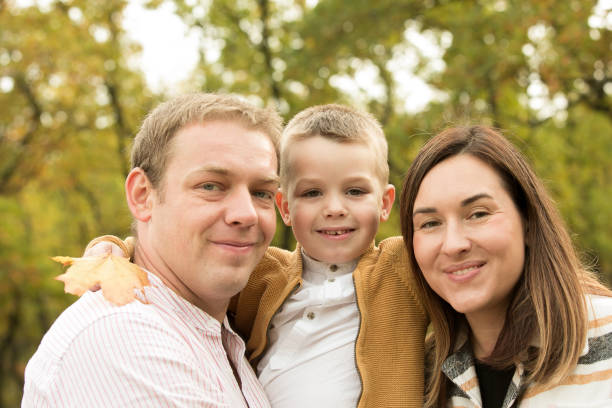 Fall. Close-up of happy family on the background of the autumn forest. Happy mom, dad and son are smiling. Fall. Close-up of happy family on the background of the autumn forest. Happy mom, dad and son are smiling. women lying down grass wood stock pictures, royalty-free photos & images