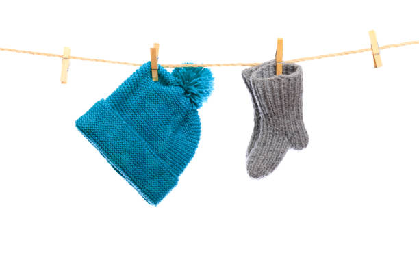 istock Baby clothes on a clothesline on white  background . knitted sock and cap - Image 1340683590