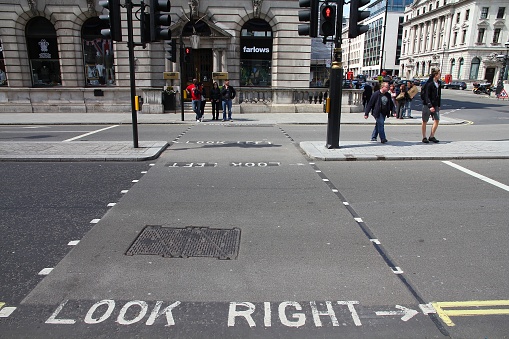 People cross the street in London. Look Right and Look Left warning signs are typical for crosswalks in the UK.