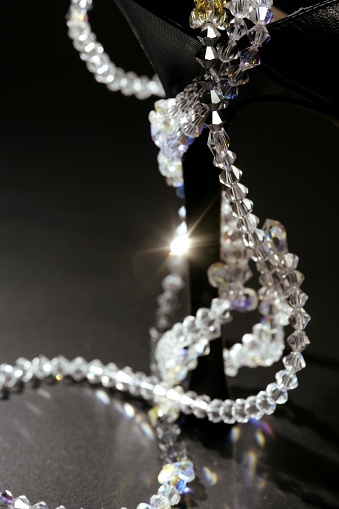 jewel necklace around a fashion black shoe heel on dark background