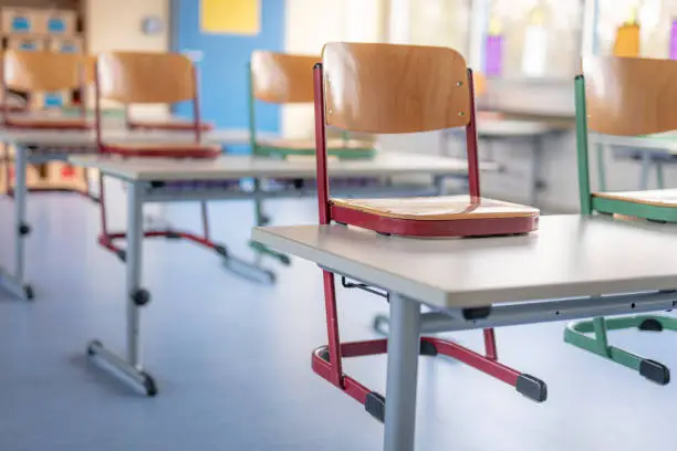 Red chair in a classroom stands on a table against a blurred background