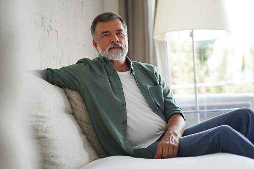 Portrait of attractive senior man sitting in sofa at home