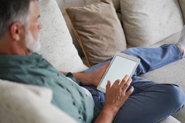 istock Mature handsome man websurfing on tablet at home. 1340688194