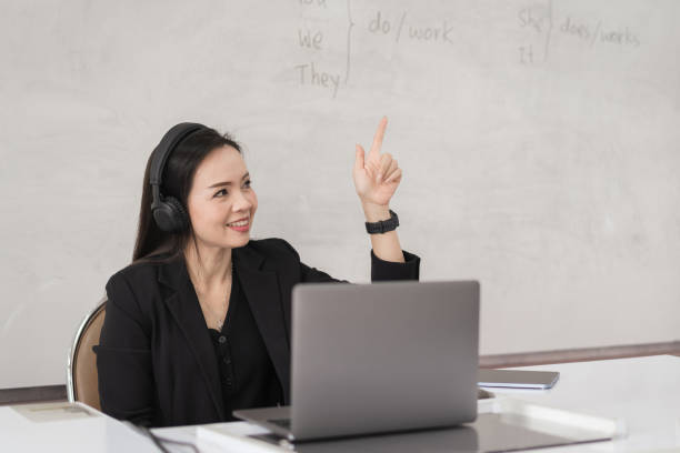 Adult Asian female college teacher teaching online via video conference meeting to students at home. Smiling Asian female tutor having video call with students. Adult Asian female college teacher teaching online via video conference meeting to students at home. Smiling Asian female tutor having video call with students. online tutors stock pictures, royalty-free photos & images