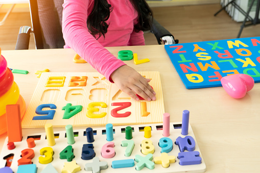 close up hands of Little girl child playing with numbers puzzle indoors at home. concept education, learning, and development intelligence life skills of children.