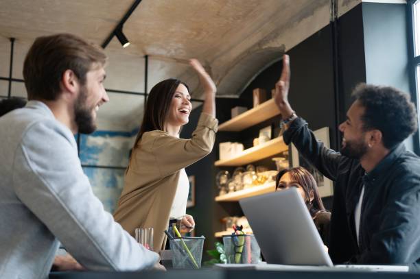 istock Two cheerful young business people giving high-five while their colleagues looking at them and smiling. 1340692189