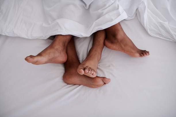 Cropped shot of an unrecognizable couple lying in bed together during the early hours of the morning at home stock photo