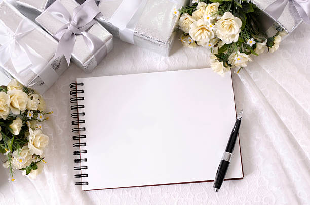 Writing book on table with wrapped wedding gifts and flowers Wedding album or writing book laid on bridal lace with several silver wedding gifts and white rose bouquets.  Alternative version of this file shown below: guest book photos stock pictures, royalty-free photos & images