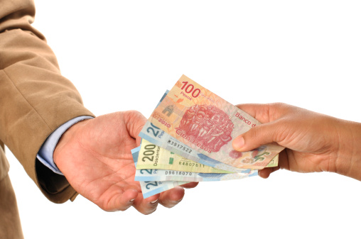 Closeup of woman handing Mexican pesos to man, on white background