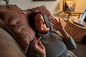 Shot of a young woman lying on the couch after her phone fell on her face