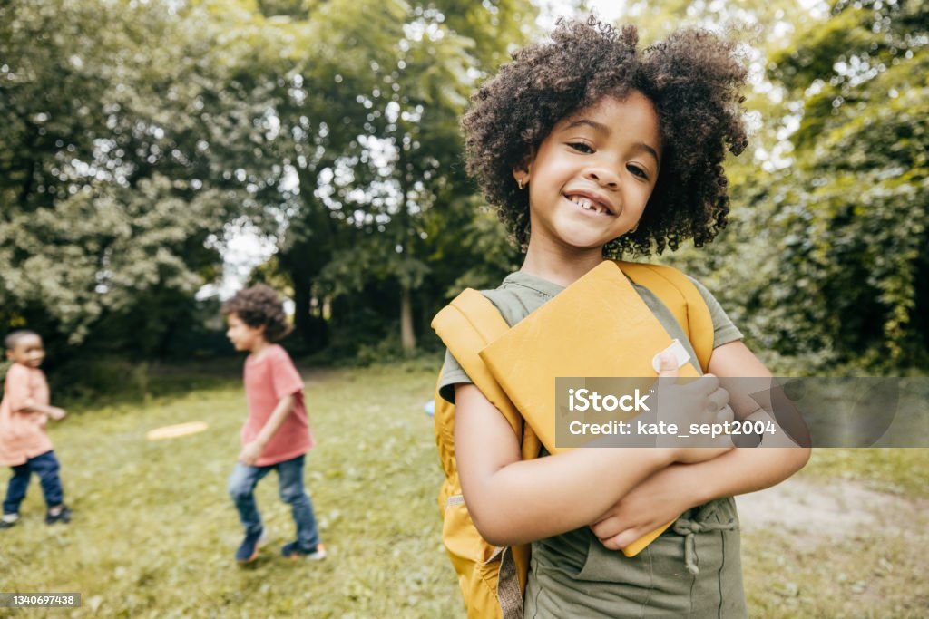 Maximizing Learning and Engaging Students Shot of cute elementary school girl smiling and looking at camera meanwhile her school friends are in the background. Back to School Stock Photo