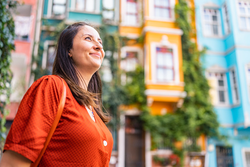 A portrait of a beautiful woman in front of colorful buildings in the city.